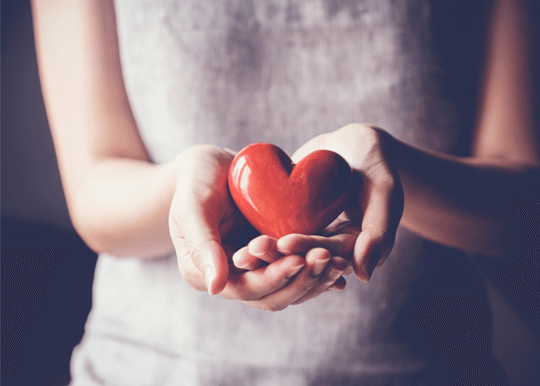 Community Giving: Close up of woman's hands holding a glass heart.