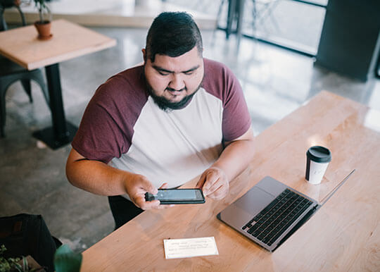man making mobile deposit with phone at cafe