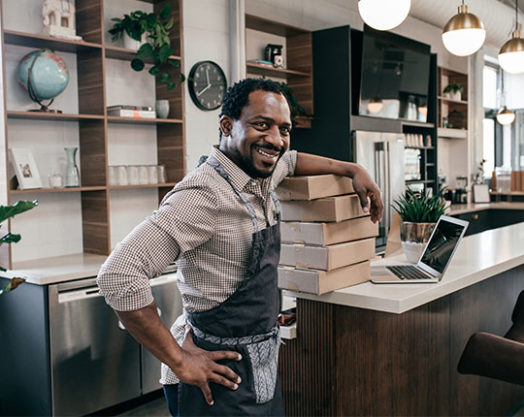 Portrait of smiling entrepreneur in coffee shop with the boxes.
