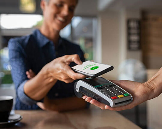 Mujer pagando la cuenta a través del smartphone mediante tecnología NFC en un restaurante.